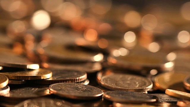黑光下的硬币在地板上堆积的特写，商业和金融省钱或投资背景的概念，非常近，浅景深