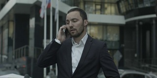俄罗斯商人在办公室外面接听电话，向商业伙伴解释一些事情