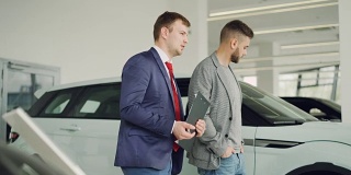 一个严肃的人正在汽车展厅和汽车经销商讨论新车型，推销员拿着文件。购车以人为本的理念。