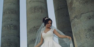 美丽可爱的新娘站在古老的柱子旁