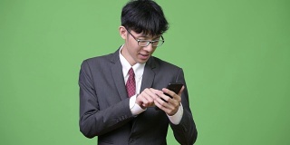年轻快乐的亚洲商人使用电话和得到好消息