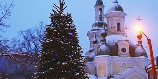 派尔努,爱沙尼亚。圣诞树在节日新年节日照明和圣凯瑟琳东正教教堂的背景