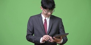 年轻快乐的亚洲商人微笑着使用数字平板电脑