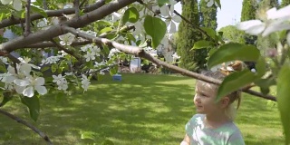 小女孩闻着树上的花，被旁边飞来飞去的蜜蜂吓坏了