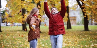 快乐的年轻夫妇在公园里扔秋叶