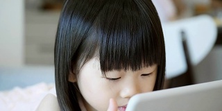 学龄前的亚洲女孩在家里使用数字平板电脑