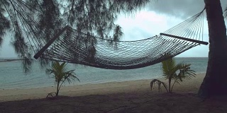 慢镜头:热带海滩上孤独的吊床在狂风暴雨中摇摆。