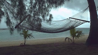 慢镜头:热带海滩上孤独的吊床在狂风暴雨中摇摆。视频素材模板下载