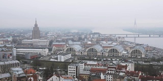 里加,拉脱维亚。顶视图城市景观在薄雾雨天。拉脱维亚科学院，建立在莫斯科斯大林摩天大楼模型，公共汽车站，国际长途汽车站和中央市场
