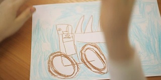男孩用铅笔在纸上画汽车轮子