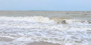 可爱的女孩在沙滩上玩海浪。海上的弱风暴，大风大浪。暑假，快乐童年的概念。