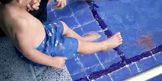 宝宝在游泳池里踢腿。