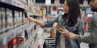 一位年轻女子在食品店挑选茶叶，她的丈夫和儿子帮她看产品和交谈。以超级市场的概念购买食物和饮料。