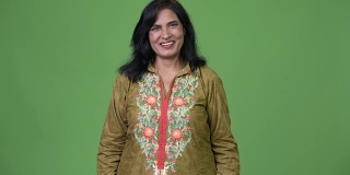 成熟快乐美丽的印度女人微笑着，穿着传统的衣服在绿色的背景下