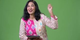 成熟、快乐、美丽的印度女人正在使用数字平板电脑，并获得了好消息