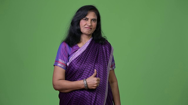 成熟美丽的印度女人在穿着纱丽传统服装时竖起大拇指