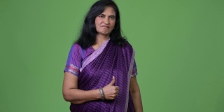 成熟美丽的印度女人在穿着纱丽传统服装时竖起大拇指