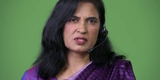 近距离拍摄成熟美丽的印度女人作为呼叫中心代表在耳机上讲话