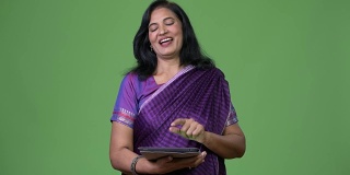 成熟快乐美丽的印度女人微笑着使用数字平板电脑