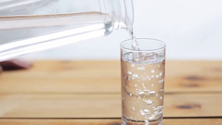 水从瓶子倒进木桌上的玻璃杯里视频素材模板下载