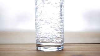 水从瓶子倒进木桌上的玻璃杯里视频素材模板下载