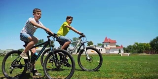 两个朋友一起骑自行车在绿色的草地上