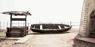 一条旧木船在一条山河的岸边。镜头。一艘破旧的渔船停在靠近水井的沙滩上