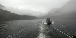 拖船在雾在太平洋的水在背景山脉阿拉斯加。