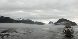 拖船在雾在太平洋的水在阿拉斯加的背景山。
