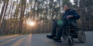 一个残疾人正坐在电动轮椅上沿着道路行进