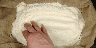 俯视图:人的手触摸一个囊中的小麦粉