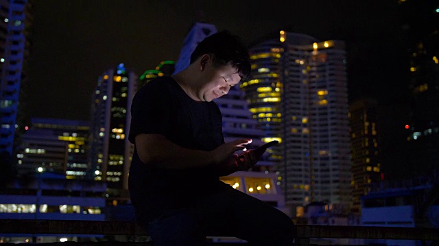 年轻人晚上在城市里低头看智能手机