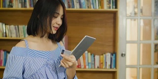 年轻的亚洲美女在家里使用数码平板电脑