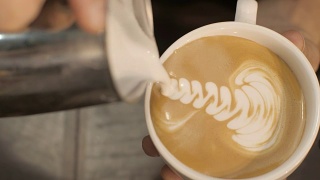 咖啡师把牛奶倒进热咖啡里，在咖啡馆里画叶子视频素材模板下载