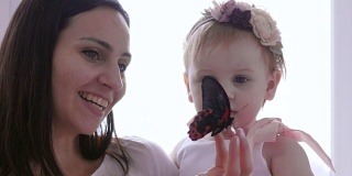 小女孩惊奇地看着虫子，小妈妈给女儿特写手拿活蝴蝶