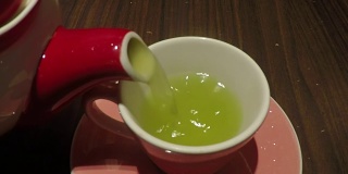 特写绿茶倒进玻璃茶杯，慢动作