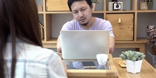 4k视频场景的商人在休闲西装坐着，抱怨后方的商业女性在现代的共同工作空间，夫妇和同事的概念与科技笔记本电脑