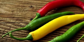 木质背景上的辣椒。质朴的木桌上放着五颜六色的辣椒。原始的健康食品。