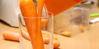 将榨好的胡萝卜汁倒入玻璃杯中。