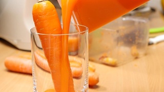 将榨好的胡萝卜汁倒入玻璃杯中。视频素材模板下载