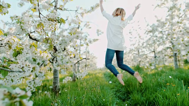 慢动作女人在樱花中快乐地跳跃