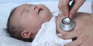 儿科医生检查婴儿。两个月大的亚洲女婴躺在医院病床上。