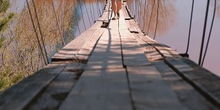 特写镜头中的家庭妈妈，爸爸和女儿走在河上的旧吊桥上。