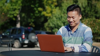 满意的亚洲人与笔记本电脑在夏季阳台上工作视频素材模板下载