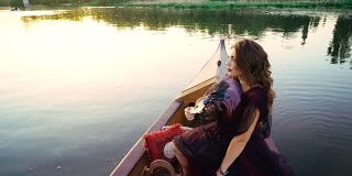 Уoung一个穿着红色裙子的女人在河上的一条船上。