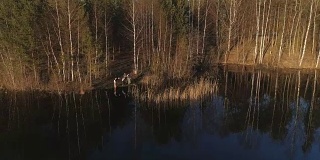 人们在森林里的河上钓鱼。飞行航拍视频。