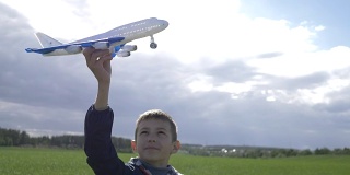 快乐的男孩梦想家手里拿着一架飞机，看着他