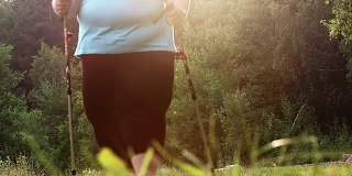 一个超重的女人在森林小径上行走。减肥和积极的生活方式主题。