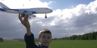 梦想家男孩手里拿着一架飞机，看着他