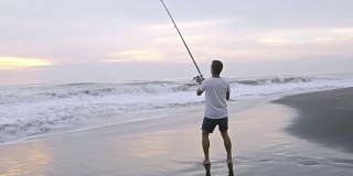 一名男子早晨在海洋海滩钓鱼